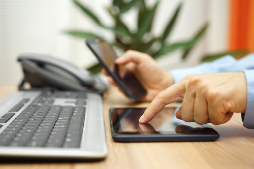 Businessman's hand using a tablet to contact Cascade Tel